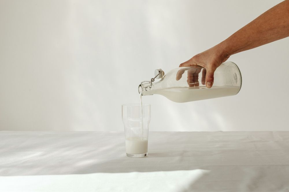 A2 milk from a glass jar being poured into a clear glass