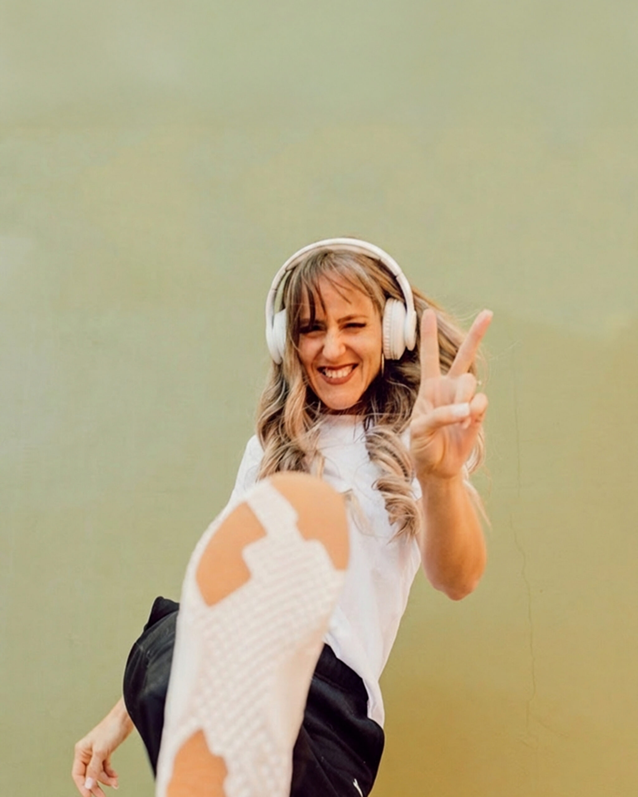 A woman wearing headphone holding up a peace sign for episode 37 of the podcast